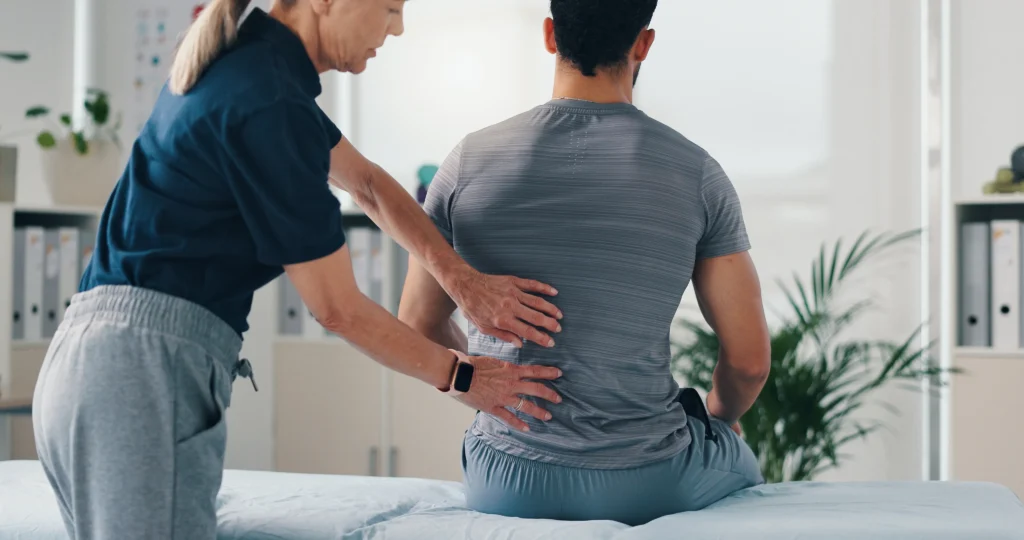 Back pain therapy: Physical therapist assessing patient. Work injury rehab & mobility recovery at our rehabilitation clinic