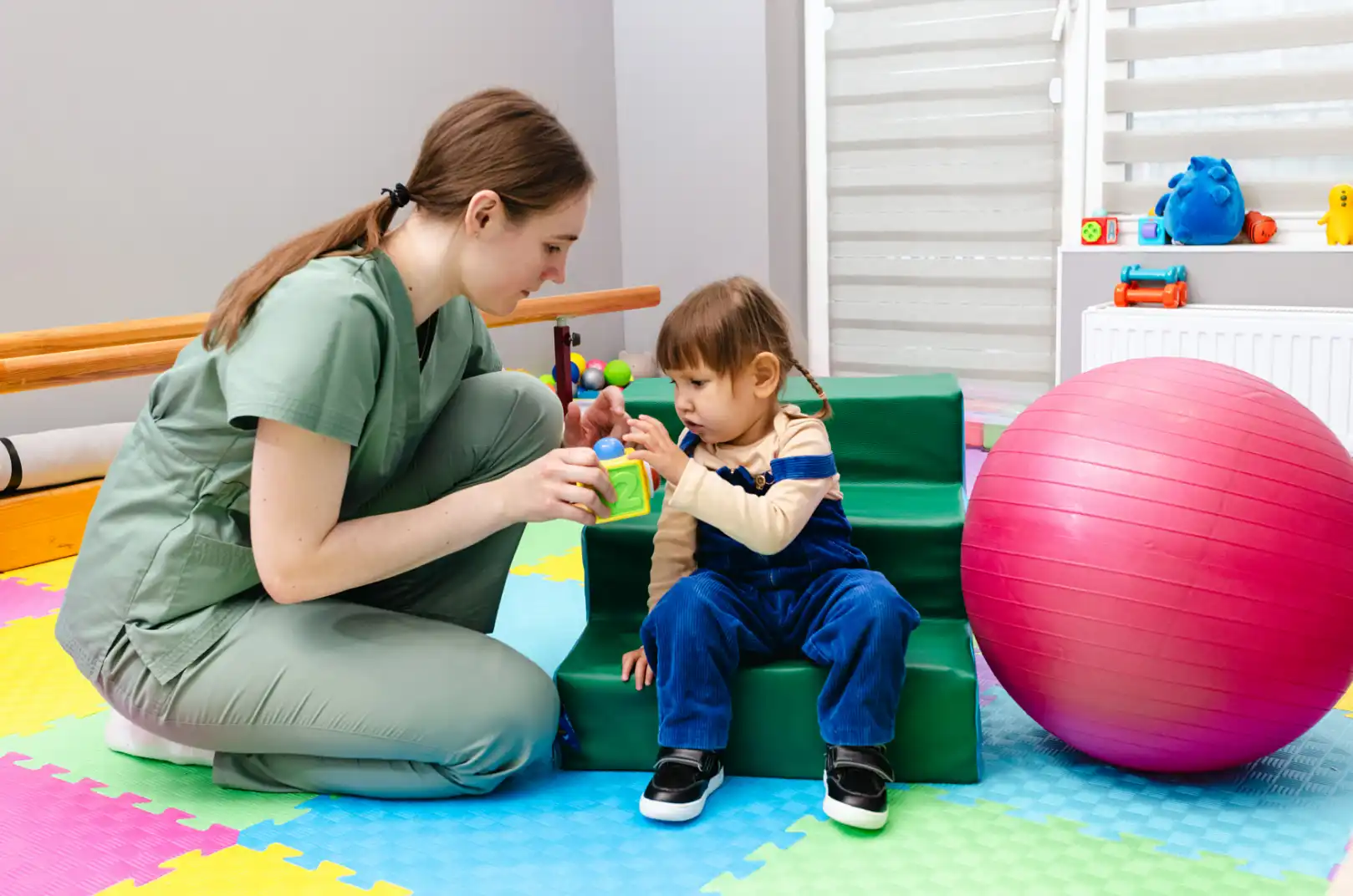 Pediatric physical therapy: Therapist helps child improve mobility. Rehab treatment for faster injury recovery and pain relief.