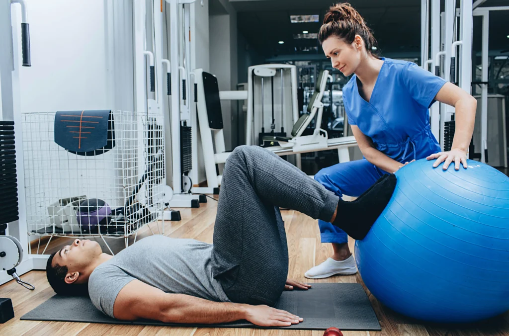 Work injury rehab: Physical therapist assisting patient with exercise for pain relief and mobility recovery at rehabilitation clinic