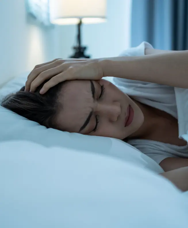Head pain treatment: Woman in bed seeking pain relief. Physical therapy for neck pain relief and mobility recovery.