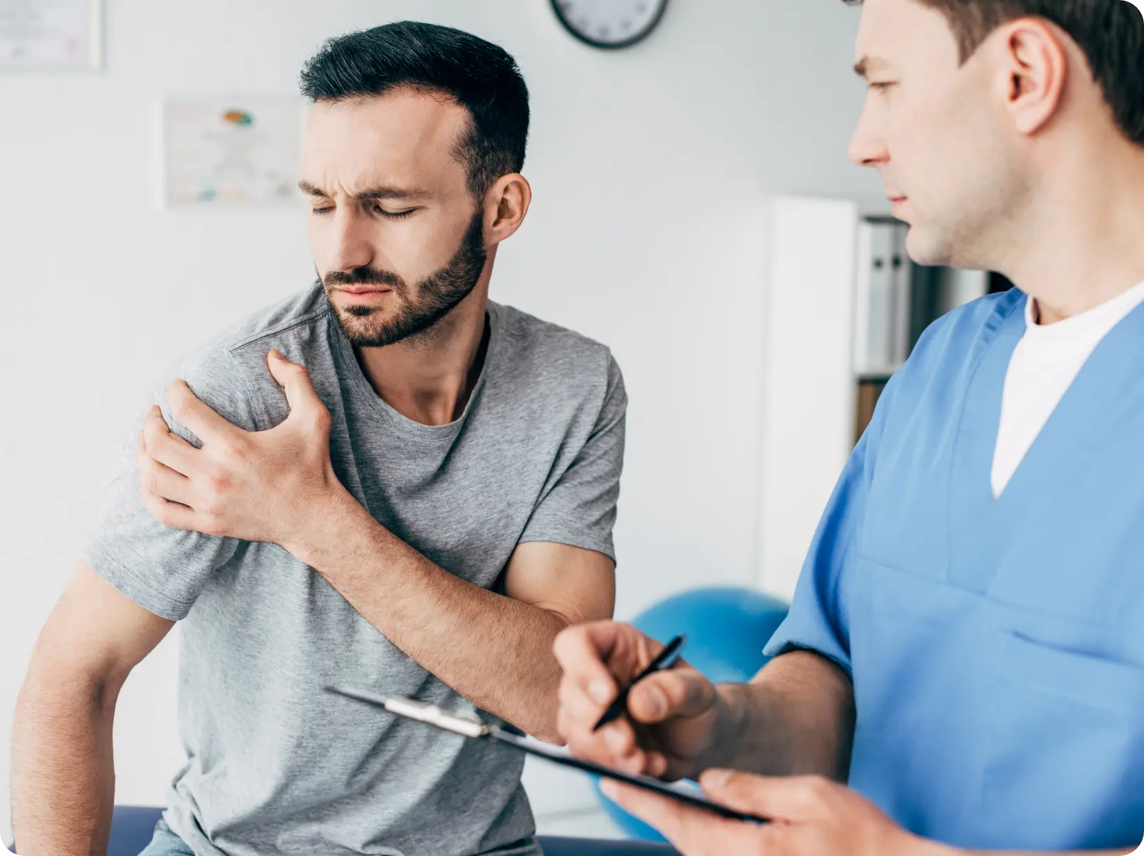 Work injury rehab: Patient consults with physical therapist for shoulder pain relief and mobility recovery at rehabilitation clinic